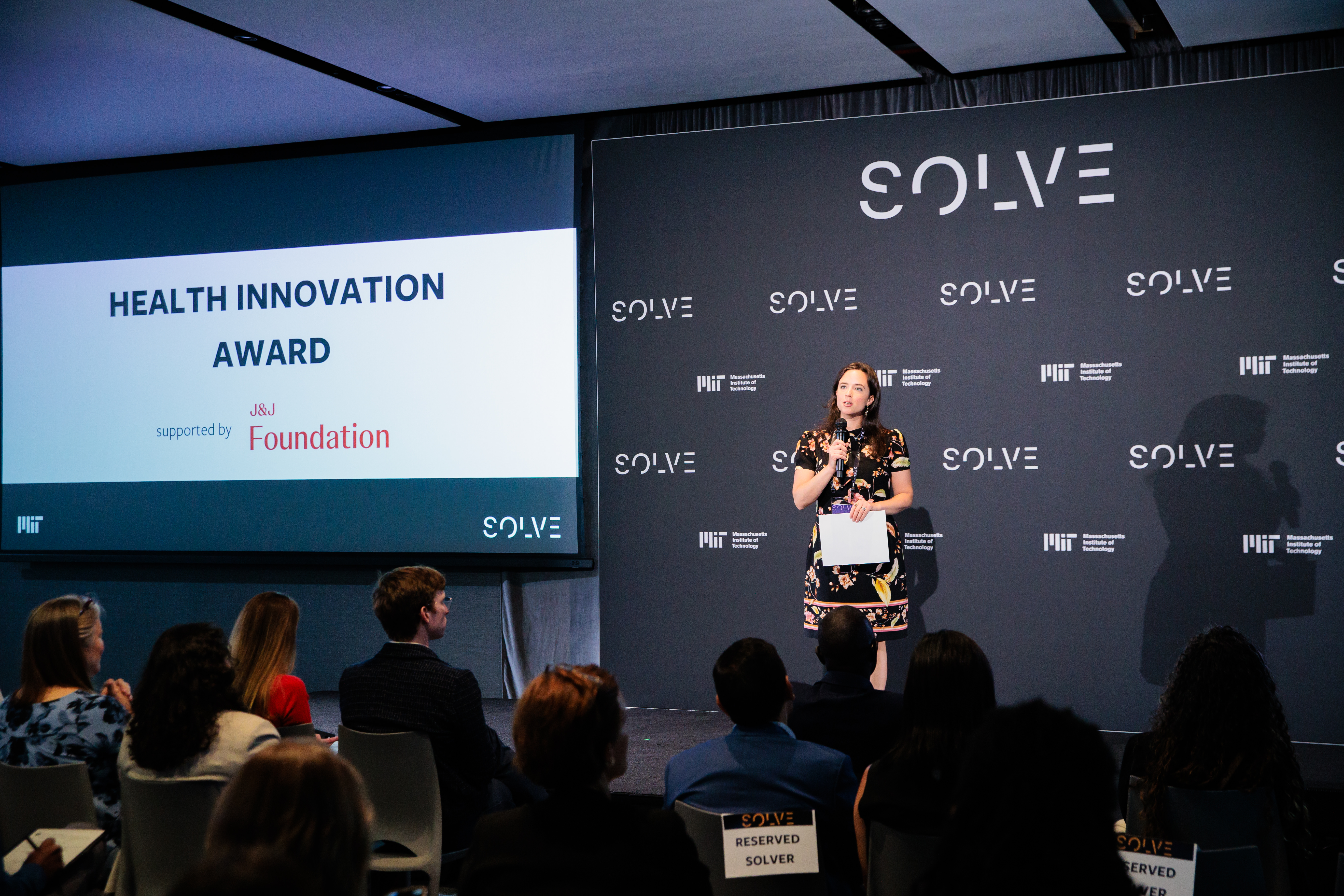 Speaker presenting the Health Innovation Award on stage at a MIT Solve event.