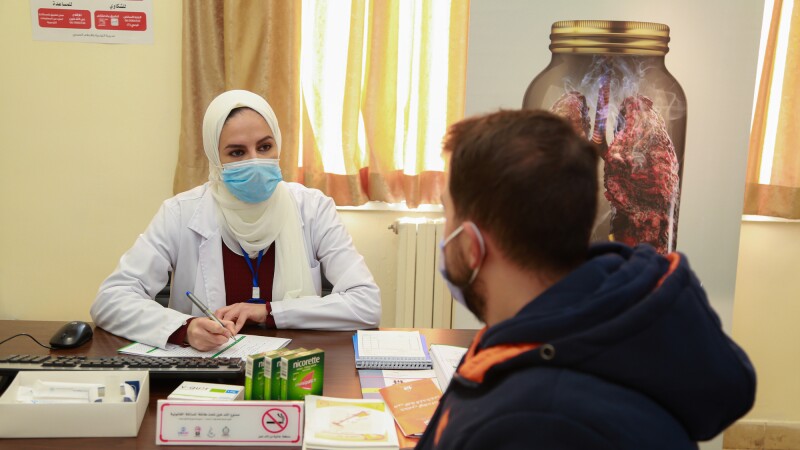 A man talks to a healthcare worker who has Nicorette boxes in front of her