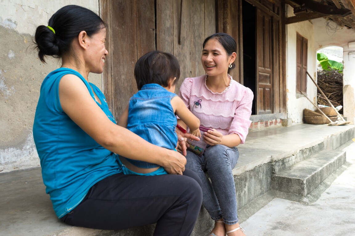 A health worker meets with a family outside their home in Vietnam