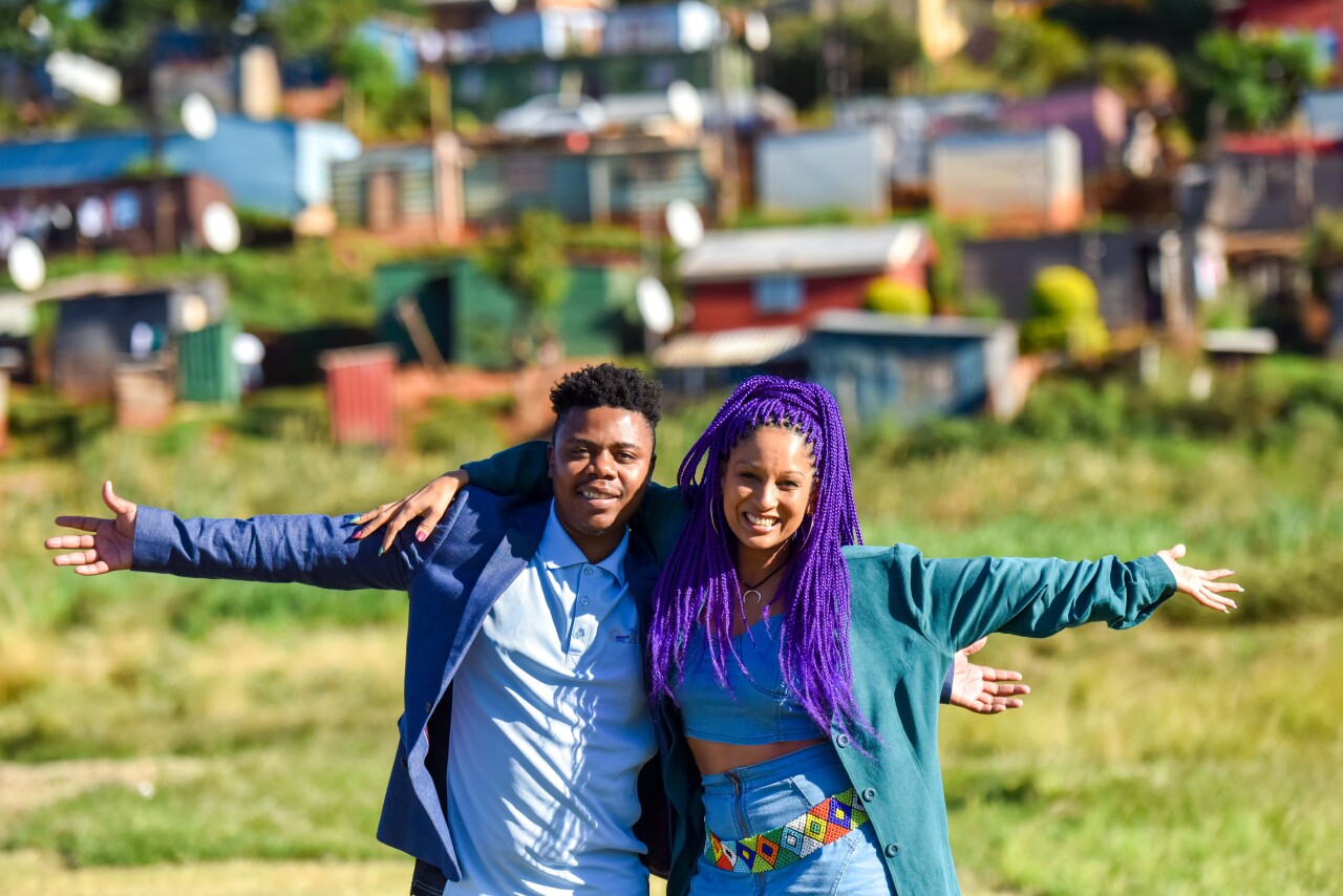 Teenage male and female hugging and smiling at the camera, both wearing bright blue colors.