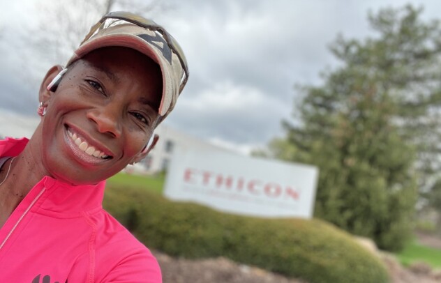 A woman in running gear stands outside in front of an Ethicon sign
