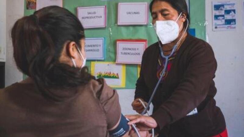 Woman checking patient's blood pressure