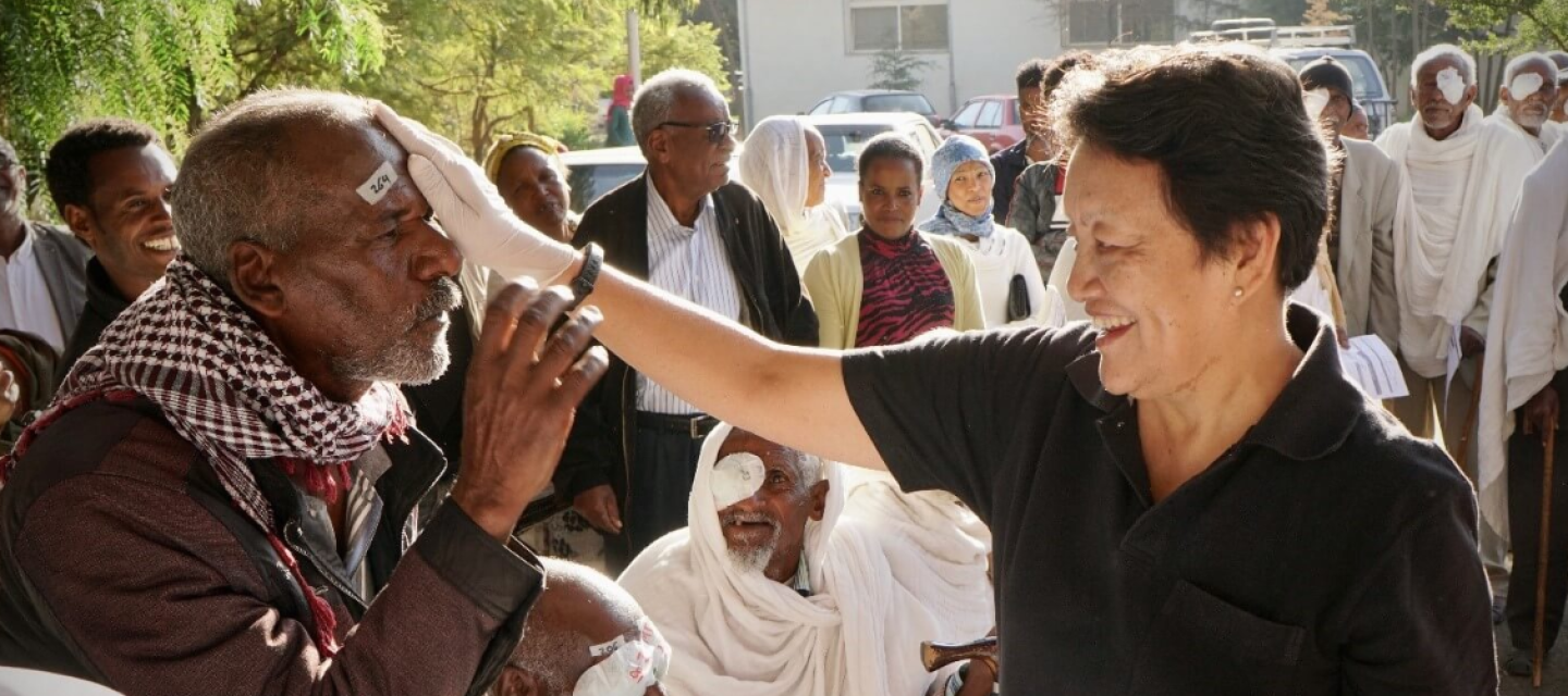 Dr. Reeta Gurung lays his hand over the eye of a patient in Eritrea.