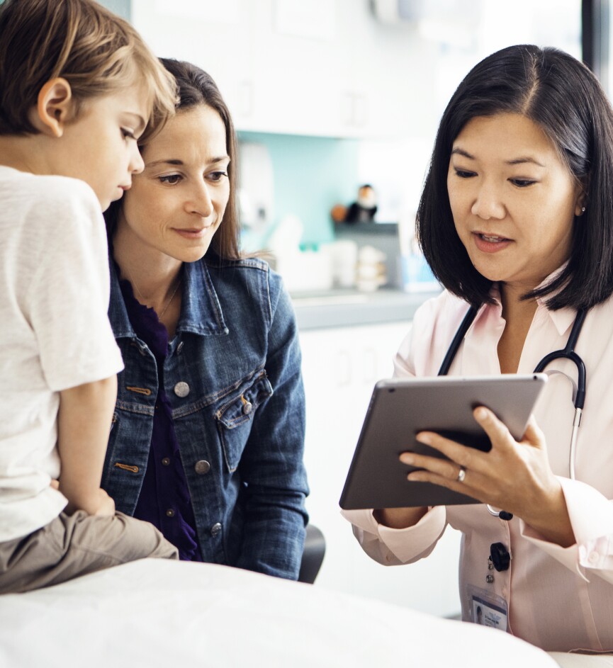 Doctor explaining report on tablet computer to family in clinic