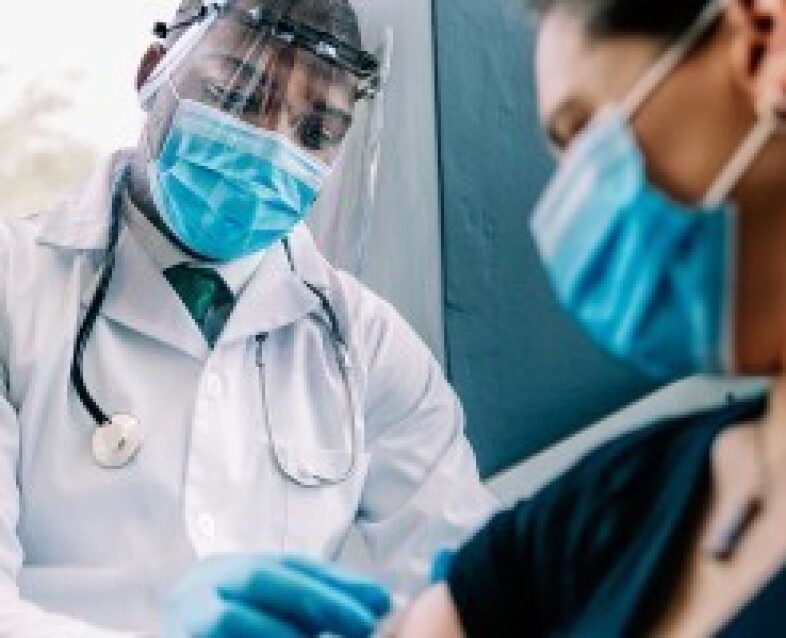 physician administering COVID-19 vaccine to patient